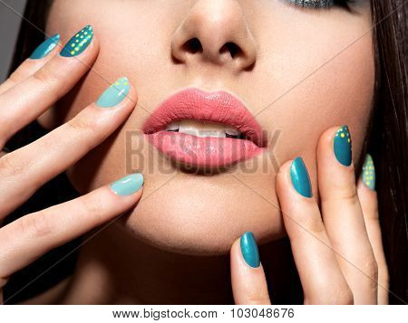 Woman's fingers with motton blue color of the nails on the face