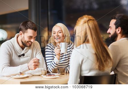people, leisure and communication concept - happy friends meeting and drinking tea or coffee at cafe