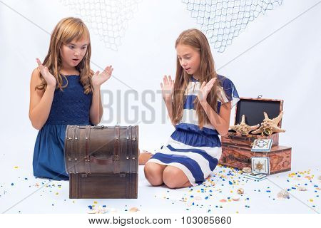 Two beautiful teen girls surprised sitting on the floor near opened chest