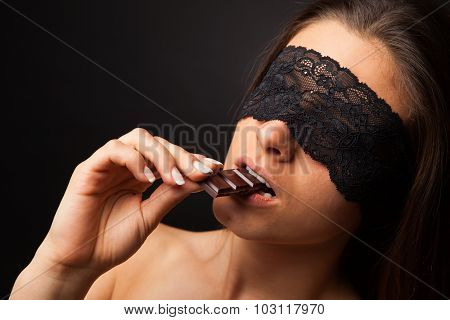 Beautiful woman with blindfold sexy eating chocolate