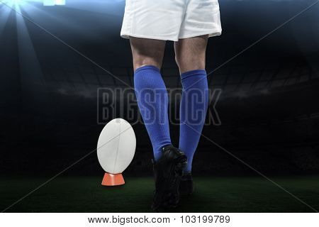 Low section of rugby player going to kick the ball against rugby stadium