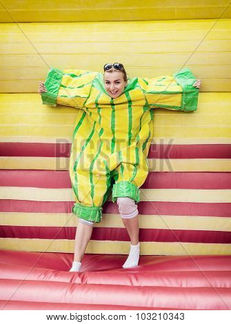 Young Woman In Plastic Dress In A Bouncy Castle Imitates A Fly On Velcro Wall