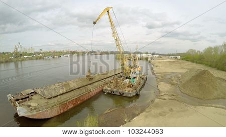 SAMARA - MAY 10, 2015: Crane and barge for sand on shore of Volga river at spring cloudy day. Aerial view video frame