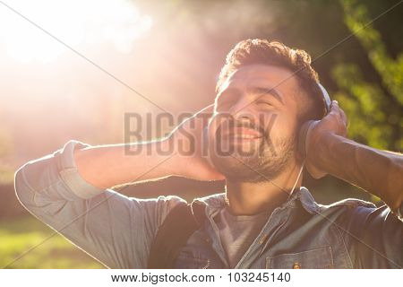 Hipster student man in earphones enjoying sunset