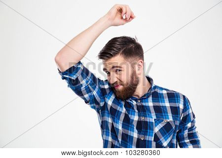 Portrait of a casual man smelling his armpit isolated on a white background