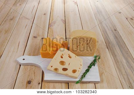 various types of fresh raw aged delicatessen cheese on white plate over light wooden table cheddar edam swiss