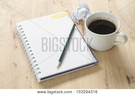 Notebook and coffee on wooden background.
