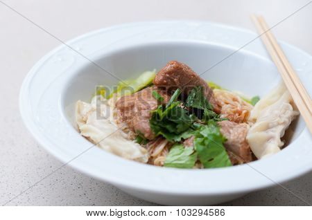 Egg noodle with delicious stewed pork and dumpling in white bowl.