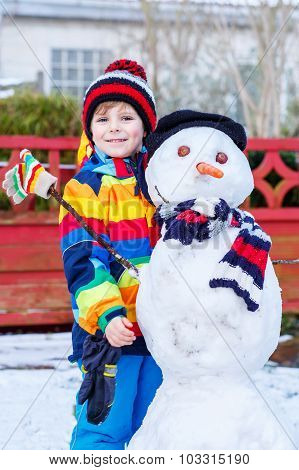 Funny Kid Boy In Colorful Clothes Making A Snowman