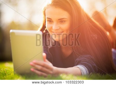 Beautiful Girl With Tablet Or Ebook Outdoor Laying On Field