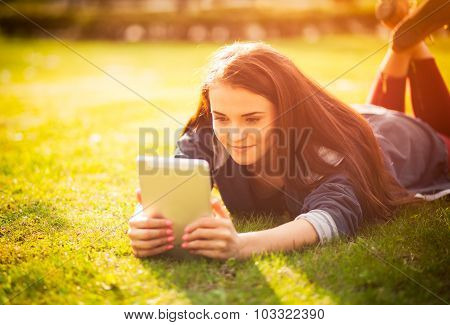 Beautiful Girl With Tablet Or Ebook Outdoor Laying On Field