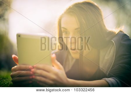 Beautiful Girl With Tablet Or Ebook Outdoor Laying On Field