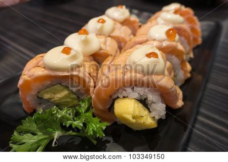 Salmon Sushi Roll with Tamagoyaki on black ceramic plate
