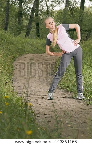 Beautiful Young Blonde Woman Warming Up On A Forest Footpath