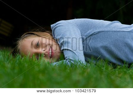 Cute child girl lay in grass smiling