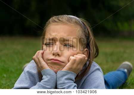 Sad and angry child lay in garden