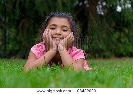 Small Gypsy Child Girl Lay In Grass Having Head In Hands