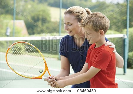 Female Tennis Coach Giving Lesson To Boy