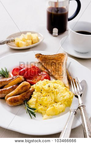 Scrambled eggs with fried tomatoes, pork sausages chipolata and wholemeal toast, full breakfast served with coffee