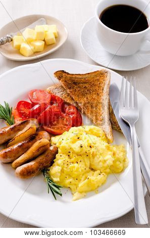 Scrambled eggs with fried tomatoes, pork sausages chipolata and wholemeal toast, full breakfast served with coffee