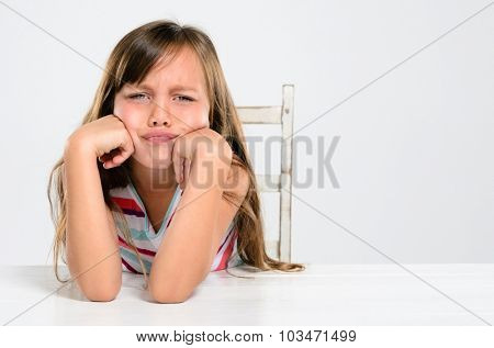 Portrait of young preschool girl pouting and throwing a tantrum at a table
