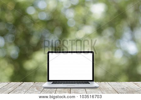 Laptop Computer On Wooden Floor With Defocus Of Garden Background. White Screen.