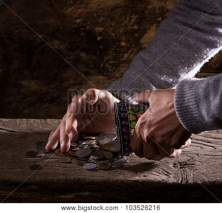 caucasian old man's hands and pile of old coins