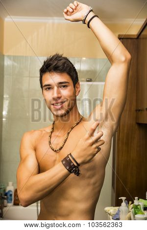 Handsome young man in bathroom, spraying cologne or perfume