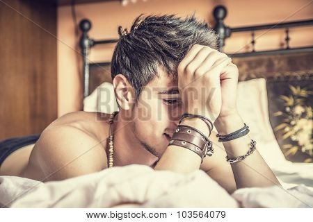 Shirtless sexy male model lying alone on his bed