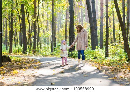 Mother and daughter walking in the autumn park