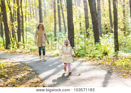 Mother and daughter walking in the autumn park