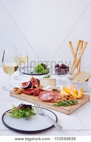 Cheese and charcuterie pairing, chorizo salami, served with fresh fruit rockmelon, fig with olives, salad and white wine