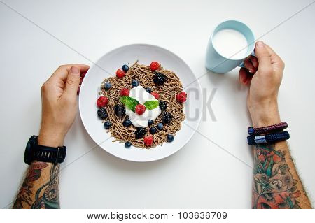 Top View Two Tattooed Hands And Plate With Integral Muesli With Berry Mix And Glass Of Milk