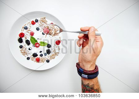 Muesli With Milk And Berries For Breakfast; Tattooed Hand Holds A Spoon
