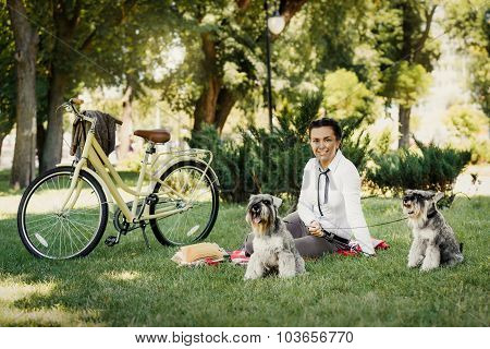Young Woman With Dogs And Bicycle Having Picnic In The Park