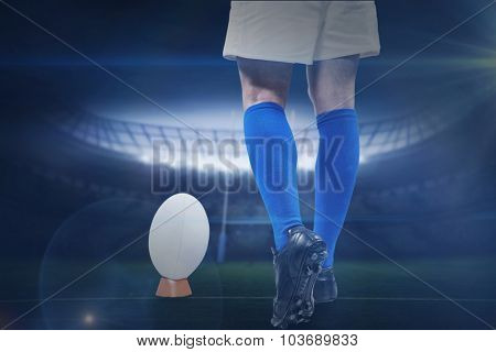 Low section of rugby player going to kick the ball against rugby stadium