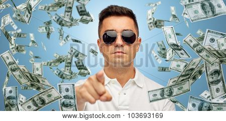 business, finance, gesture and people concept - face of middle aged latin man in sunglasses pointing finger on you over blue background with heap of falling dollar money