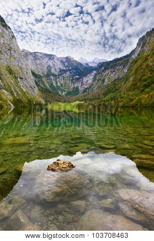 Magic reflection in German lake Koenigssee. Cloudy day on the lake. Clouds and mountains reflected in the mirrored surface of the water