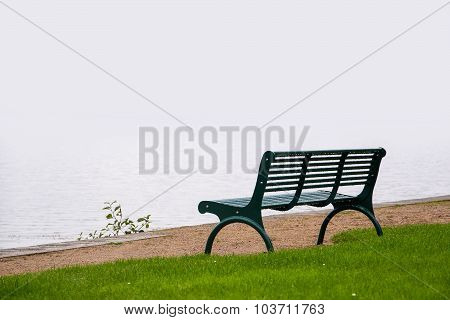 Empty Park Bench, Wet From The Rain On The Shore Of A Misty Lake