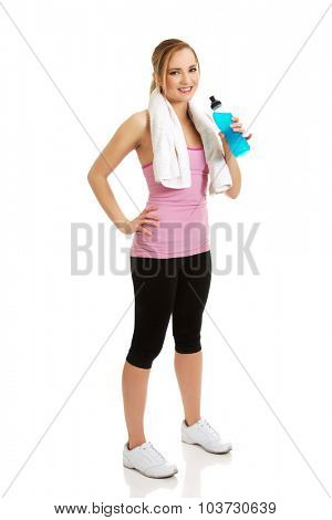 Attractive woman in fitness clothes drinking isotonic drink.