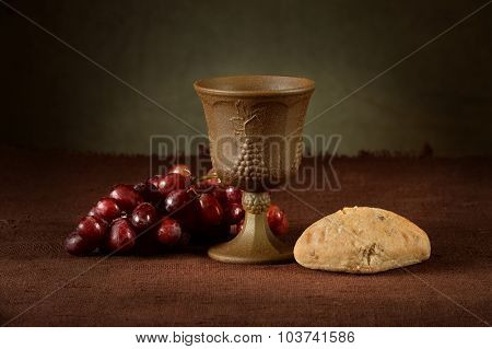 Wine cup surrounded by bread and grapes as symbols of communion