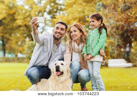 family, pet, season, technology and people concept - happy family with labrador retriever dog taking selfie by smartphone in autumnl park