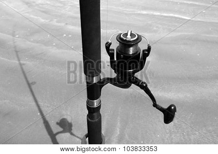 Surfcasting cast fishing pole rod line and its shadow on sandy beach. Concept photo of angling fishing fish.