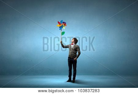 Young happy guy in casual with colorful windmill in hand