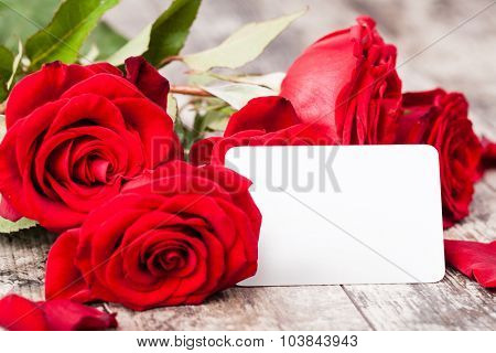 Red roses with a blank gift tag on a woodwn