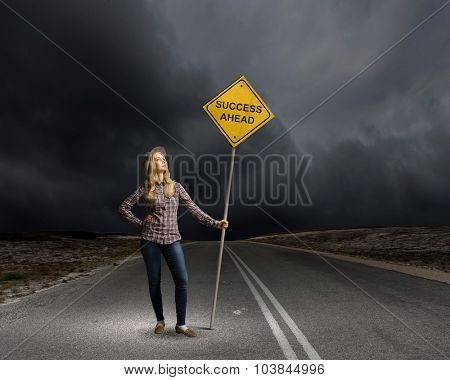 Young woman satnding on road with signboard