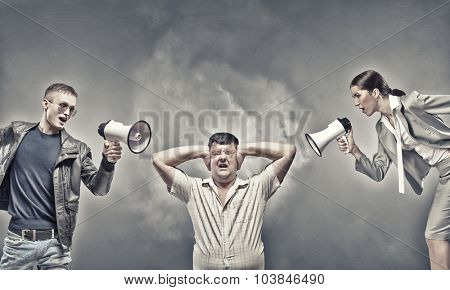 Furious people screaming agressively in megaphone at man