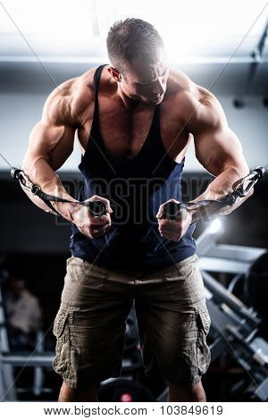 Bodybuilder doing butterfly on cable pull for better definition of his arm muscles
