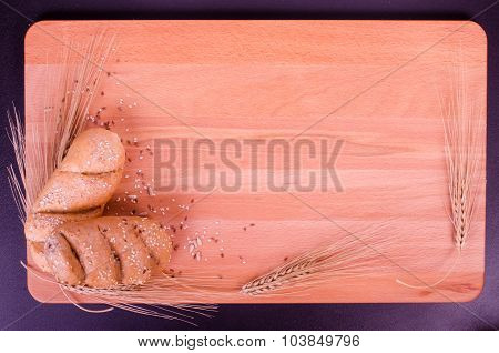 Fresh buns, cookies and wheat ears in a wood background
