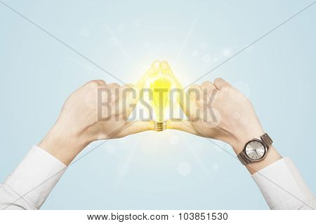 Hands creating a form with yellow light bulb in the center